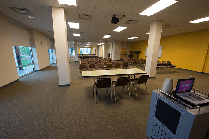 Large room with lots of chairs front table, media cart and ceiling mounted projector.