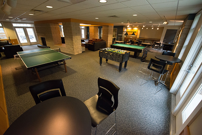 Room with pool table, foosball table and many chairs.