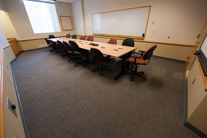 Long room with long conference table, window and dry erase boards.