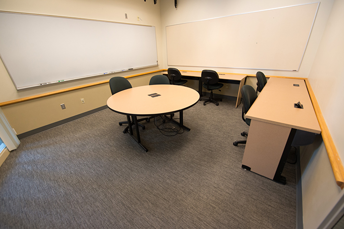 Meeting room with dry erase boards mounted on walls and three tables/desks.