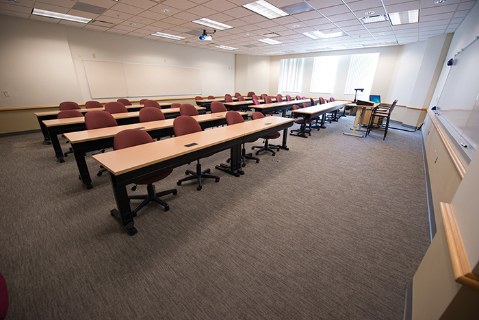 Large classroom like space with table/desks for 32+ people, plus instructors desk and dry erase boards.