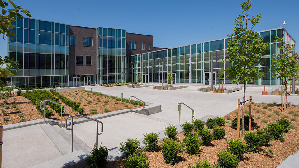 Exterior shot of glass and brick building with large foreground plaza.